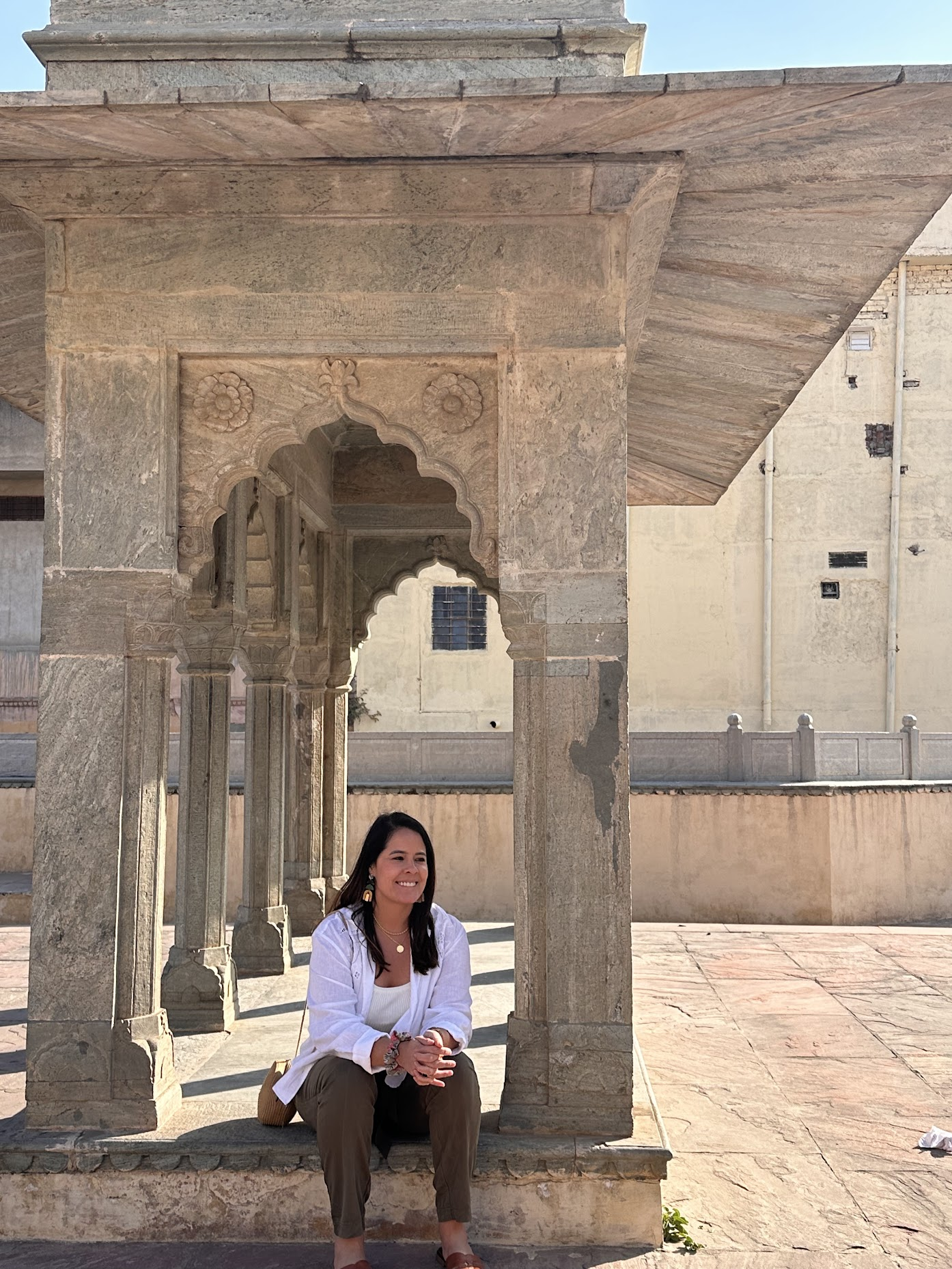 Paula sitting outdoors near stone architecture